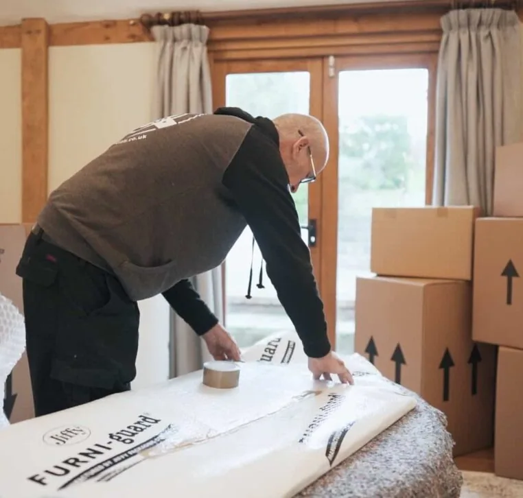 A Wolves Storage Sussex packer taping Furni-guard protection around furniture — Wolves Storage Sussex serving Bognor Regis