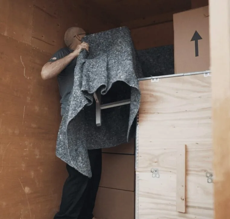 A Wolves Storage Sussex mover wrapping a chair in a protective blanket inside a storage container — Wolves Storage Sussex serving East Grinstead